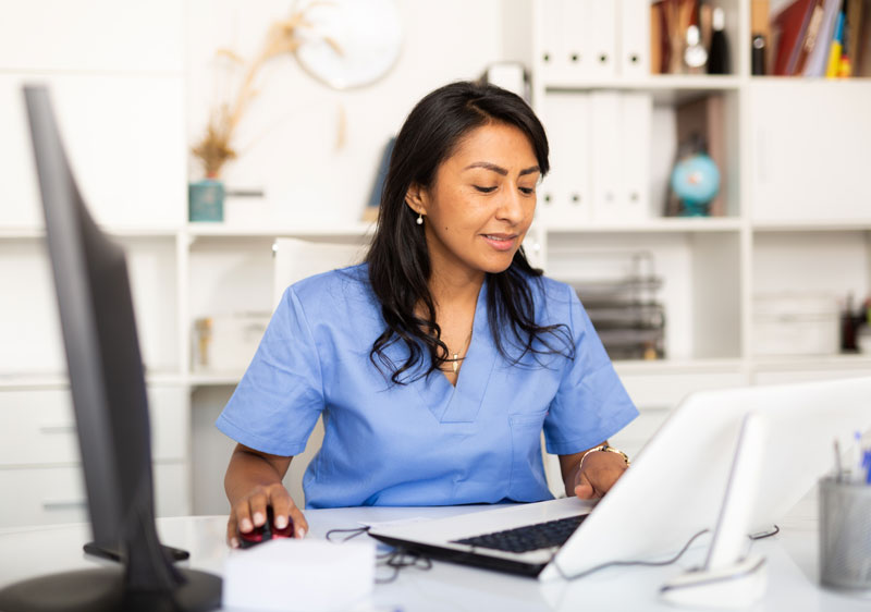 Weibliche Pflegekraft überprüft Daten am Computer.
