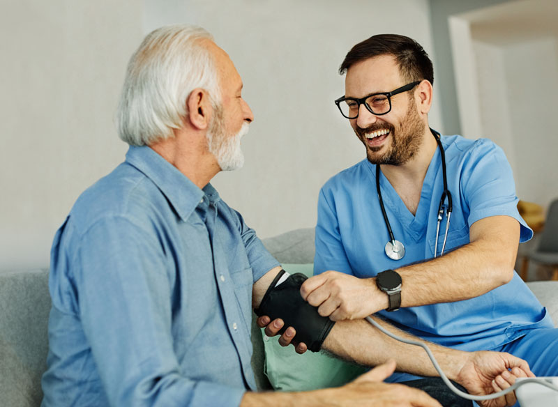 Männliche Pflegekraft überprüft Blutdruck an einem älteren Mann